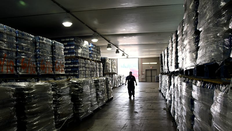 Shrink-wrapped pallets inside a trailer with one stack collapsed against the wall and boxes crushed at the corner.